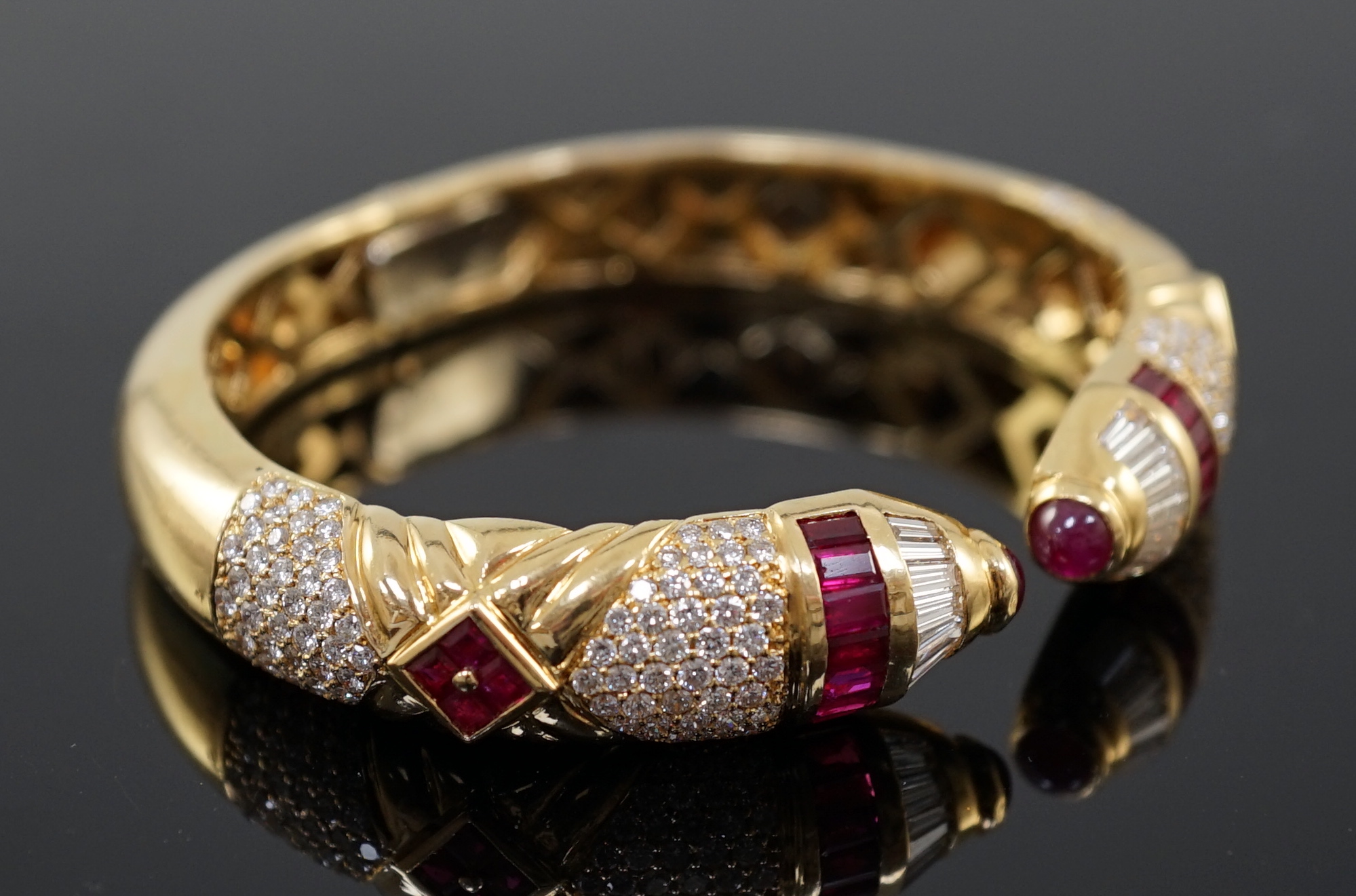 A modern 18ct gold, ruby and diamond cluster openwork hinged bangle